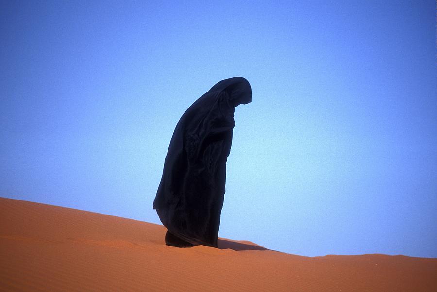 muslim woman praying on a sand dune photo