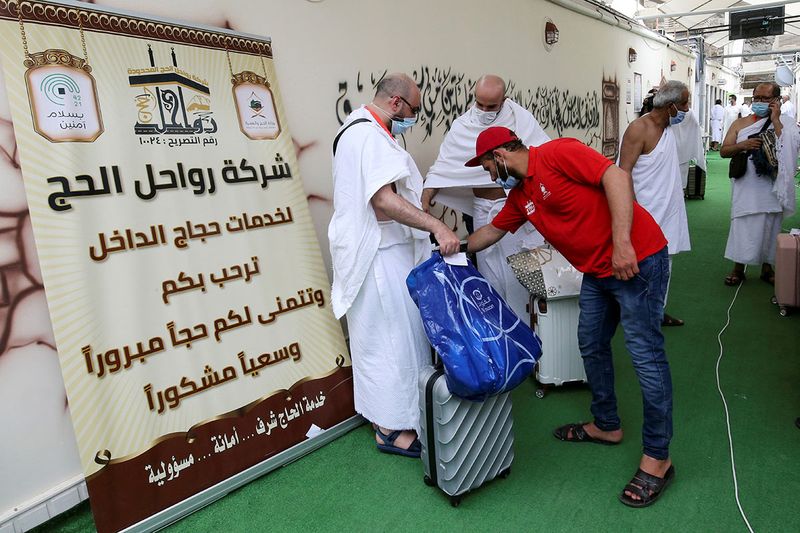 Pilgrims stand with their luggage as they arrive in the Mina area during the annual Haj pilgrimage in the holy city of Mecca Saudi Arabia July 18 2021. 17abd263292 original ratio